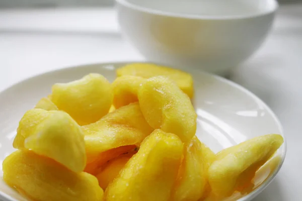 Tabakta kurutulmuş sarı meyve ve beyaz çay fincanı..