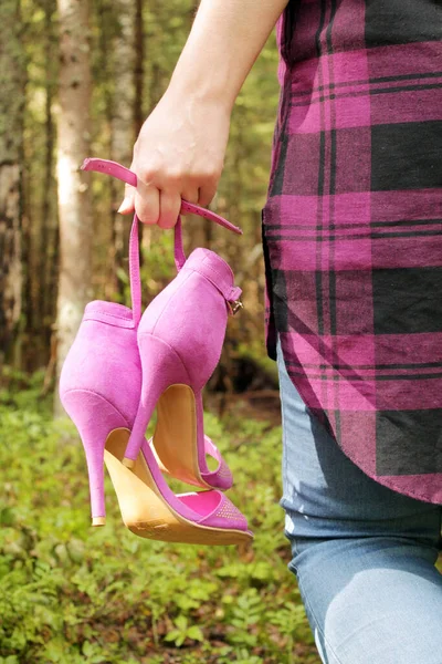 Bir kızın elinde fuşya renginde kadın ayakkabıları.