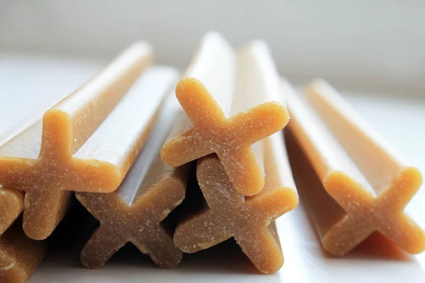 Köpek için bir ikram, beyaz arka planda kahverengi renkli lezzetli çubuklar..