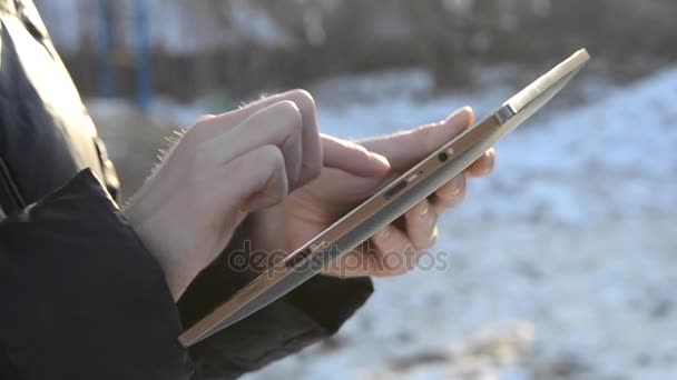 Chica voltea a través de fotos y el trabajo en una tableta al aire libre en invierno — Vídeos de Stock