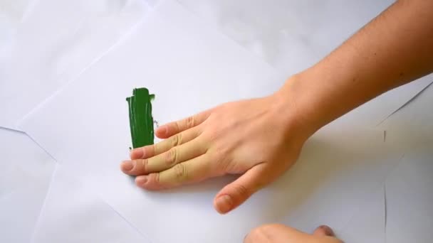 Vernice verde spalmato le mani attraverso carta bianca — Video Stock