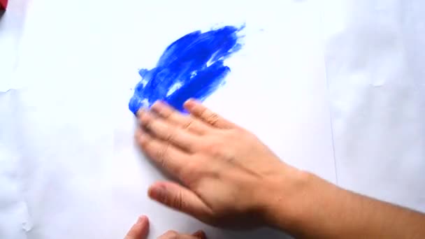 Mädchenhände malen blaue Farbe auf das weiße Papier — Stockvideo