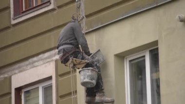 Adam kaplama, evi sıvama yüksek katlı inşaat üstünde çalışıyor