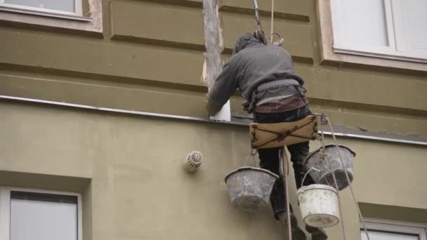 O homem trabalha em trabalhos de arranha-céus revestimento, reboco da casa — Vídeo de Stock