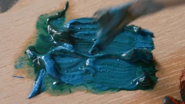 Verf, groen en blauw worden vermengd met een borstel — Stockvideo