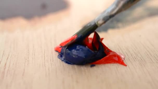 Смешивание масляной краски синего и красного цвета в палитре — стоковое видео