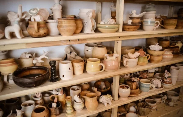 Many different pottery standing on the shelves in a pottery workshop. Low light — Stock Photo, Image
