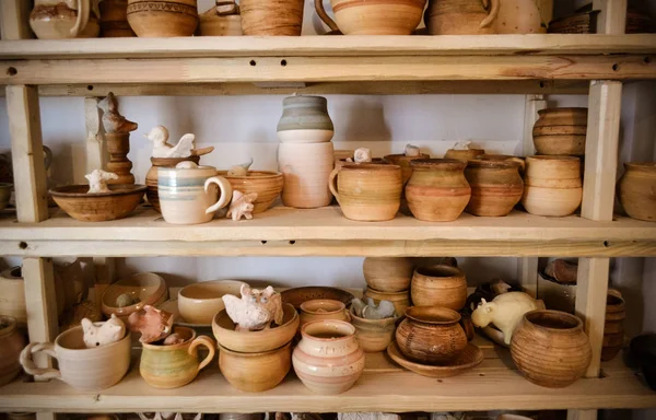 Many different pottery standing on the shelves in a pottery workshop. Low light — Stock Photo, Image