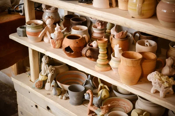 Many different pottery standing on the shelves in a pottery workshop. Low light — Stock Photo, Image