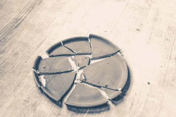 Сломанная тарелка лежит на деревянном столе — стоковое фото
