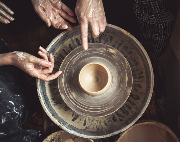 Hands of the master potter and vase of clay on the potters wheel