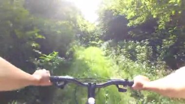 Yeşil bir ormanda bisiklet süren bisikletçi kız.