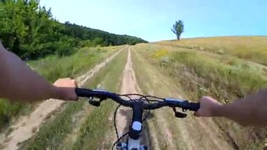 Bisiklet süren bir adam toprak bir yolda gidiyor.