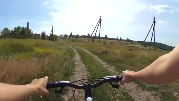 Andar de bicicleta em uma estrada de terra em um campo em um quente — Vídeo de Stock