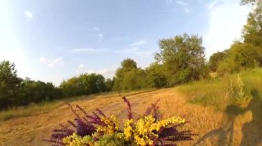 Şafak vakti bisiklet sürerim. Gün batımında çayırda çiçeklerle.