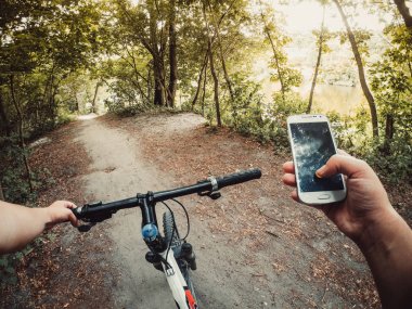Telefon ile toprak yol üzerinde ormandaki bir adam bisikletçi standları