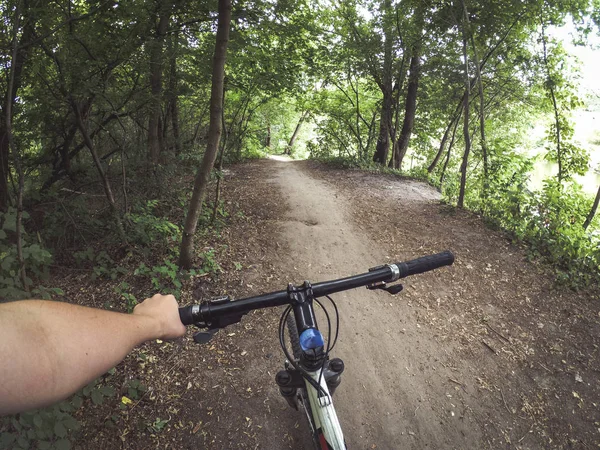 Ein Mann Radfahrer hält ein Fahrrad hinter dem Steuer mit einer Hand im Wald. — Stockfoto