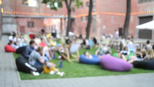 Muchas personas están sentadas en coloridas bolsas de asiento — Vídeos de Stock