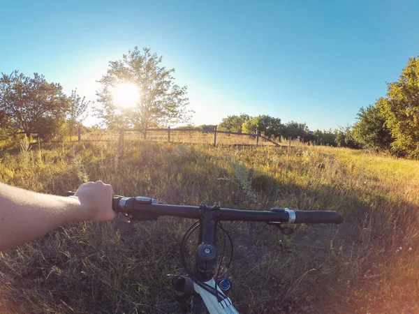 Een man houdt een wiel met één hand permanent in een veld — Stockfoto