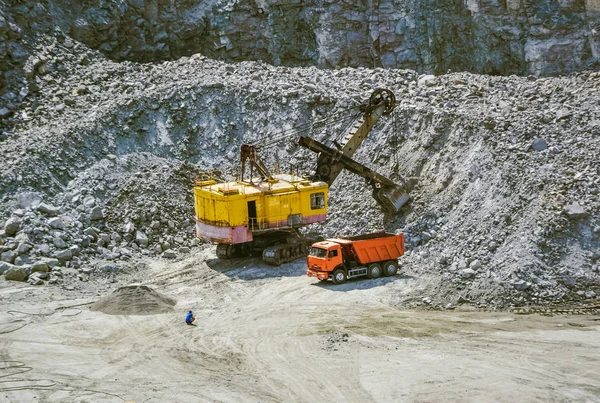 Enorme escavadeira, caminhão e homem de pé ao lado na pedreira de granito — Fotografia de Stock