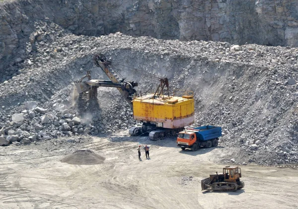 Enorme escavadeira, caminhão e homem de pé ao lado na pedreira de granito — Fotografia de Stock