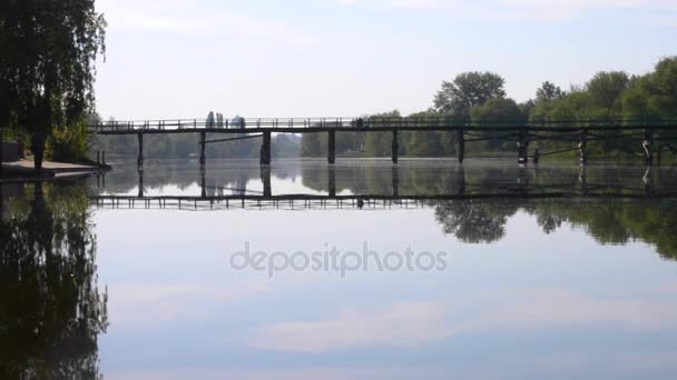 Reflexion des wolkenverhangenen blauen Himmels auf der Oberfläche des Flusses und der Brücke über den Fluss — Stockvideo