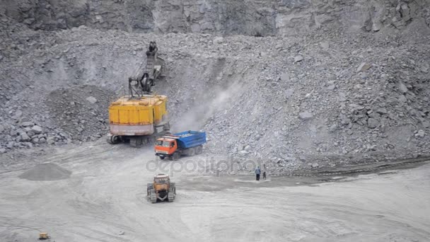 Piedras de carga de la excavadora amarilla enorme en un camión — Vídeos de Stock