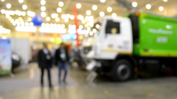 Veel auto's vrachtwagens vrachtwagen binnen de tentoonstelling paviljoen en mensen rondlopen — Stockvideo