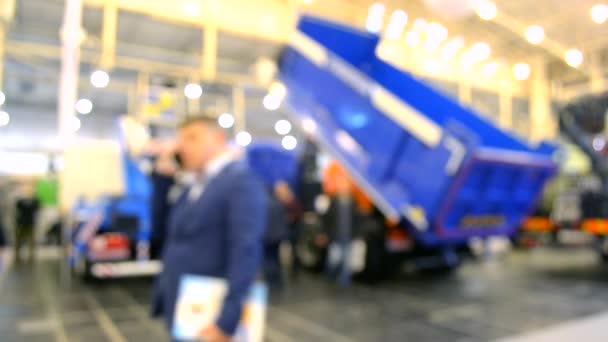 Muchos camiones de coches camiones dentro del pabellón de la exposición y la gente camina alrededor — Vídeo de stock