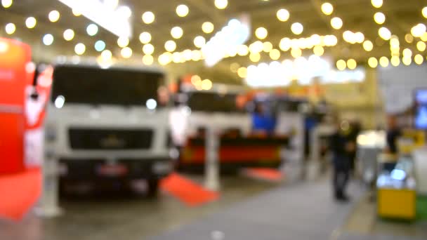 Багато автомобілів вантажівки всередині виставкового павільйону і люди ходять навколо — стокове відео