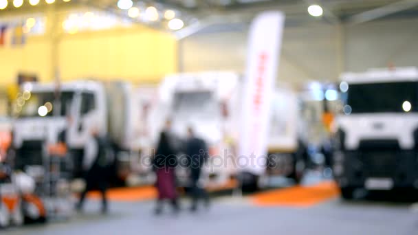 Muchos camiones de coches camiones dentro del pabellón de la exposición y la gente camina alrededor — Vídeos de Stock