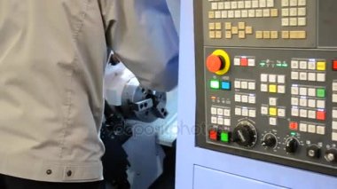 Kontrol panelinde çalışan adam endüstriyel bir makineyle çalışıyor.