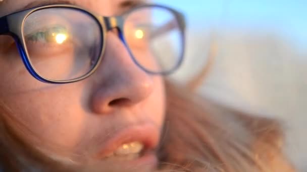 Mavi gözlük giyen bir kız portresi mesafe içine bakmak için beyaz — Stok video