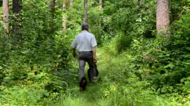 yaşlı adam ve köpeği ormanda yürüyor