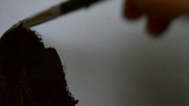 Adam bir fırça ve siyah boya ile beyaz kağıt üzerine çizer