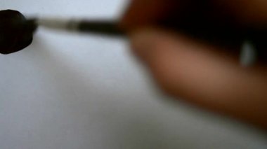 Adam bir fırça ve siyah boya ile beyaz kağıt üzerine çizer