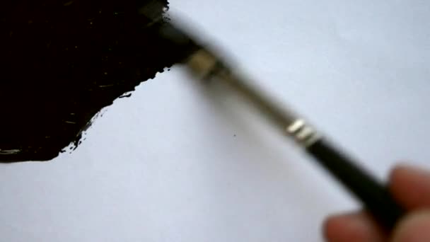 Persona pinta un pincel con una superficie blanca de pintura negra — Vídeos de Stock