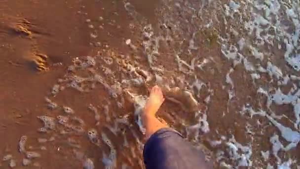 Langzame beweging. Het meisje loopt in de buurt van zee en golven rollen op haar voeten — Stockvideo