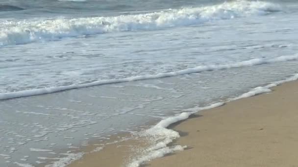 Povrch vody mořské vlny oceánu s bílou pěnou zblízka na písečné pláži. — Stock video