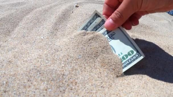 Ein Mädchen holt aus dem Sand Geldscheine von dreihundert Dollar. — Stockvideo