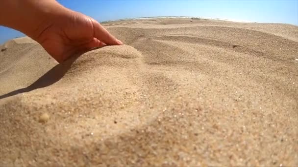 Slow motion. Girl picks up handful of sand in her palm and sprinkles — Stock Video