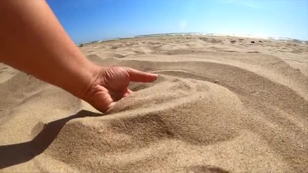 Langzame beweging. Meisje pakt handvol zand in haar handpalm en hagelslag — Stockvideo