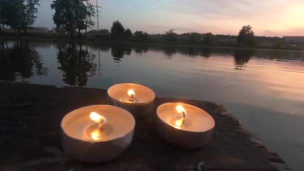 Tre candele pillola si trovano sul bordo di un vecchio pontile di legno — Video Stock