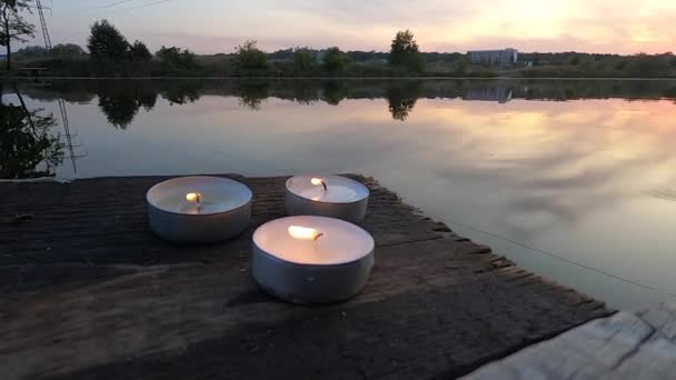 Trzy świece leżą na skraju starego drewnianego nabrzeża. — Wideo stockowe