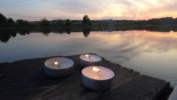 Trois bougies de pilule reposent sur le bord d'un vieux quai de planche en bois — Video