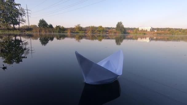 Белая лодка плавает на гладкой зеркальной поверхности озера в тишине — стоковое видео