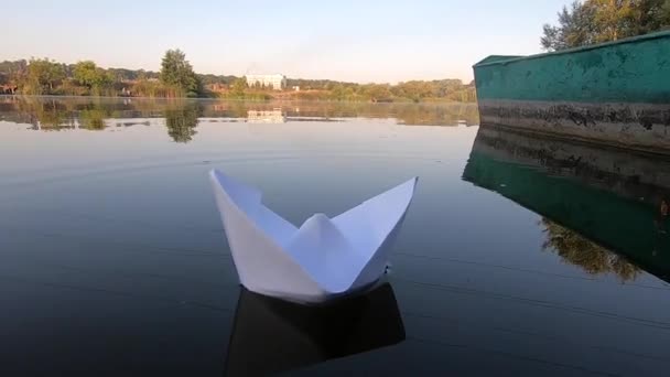 Білий човен плаває на гладкій дзеркальній поверхні ставка озера в спокої — стокове відео