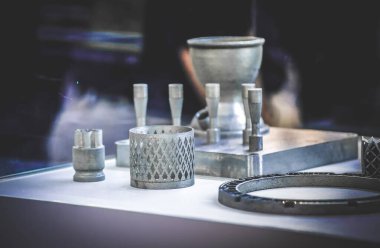 Metal 3D yazıcıya yazdırılmış nesneyi tutan adam.