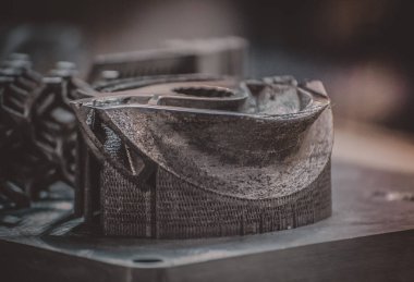 Metal 3D yazıcıya yazdırılmış nesneyi tutan adam