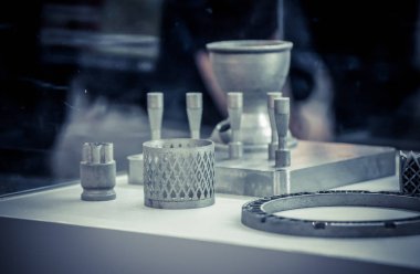 Metal 3D yazıcıya yazdırılmış nesneyi tutan adam.